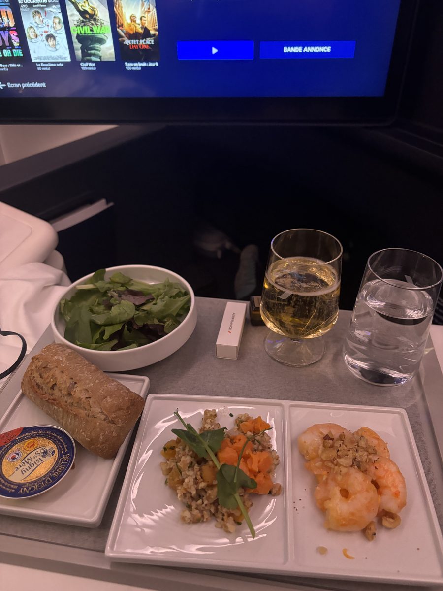 Plateau repas servi dans la cabine business bleue d'Air France, crevettes et boulgour, devant le catalogue de films à l'écran