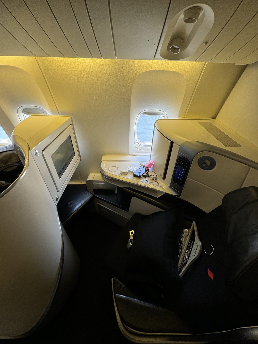 Le siège Best de la business Air France sur Boeing 777, avec sa coque blanche, sa petite tablette et son écran encastré, sous une lumière jaune