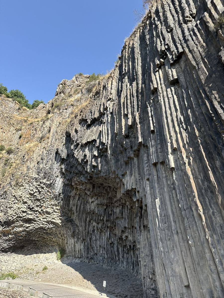 La paroi du canyon de l'Azat couverte de colonnes de basalte verticales serrées les unes contre les autres, formant une voûte en éventail au-dessus d'un éboulis