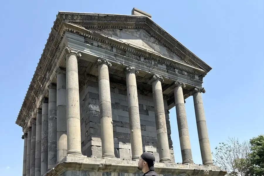 Le temple gréco-romain de Garni vu en contre-plongée : son fronton sculpté et sa colonnade de basalte se détachant sur un ciel bleu sans nuage