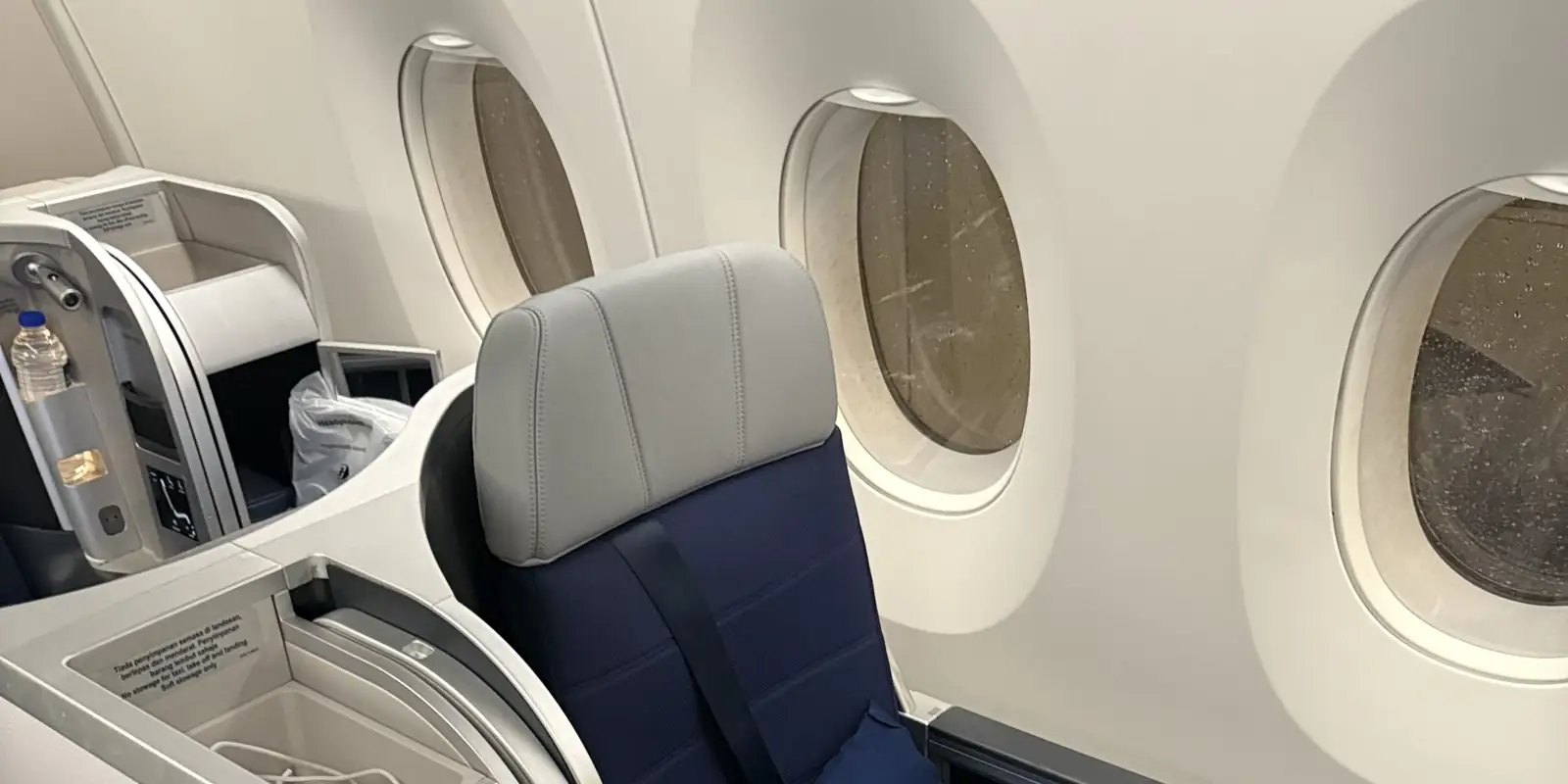Siège de classe affaires vide de Malaysia Airlines avec hublots, étiquette de sécurité en malais