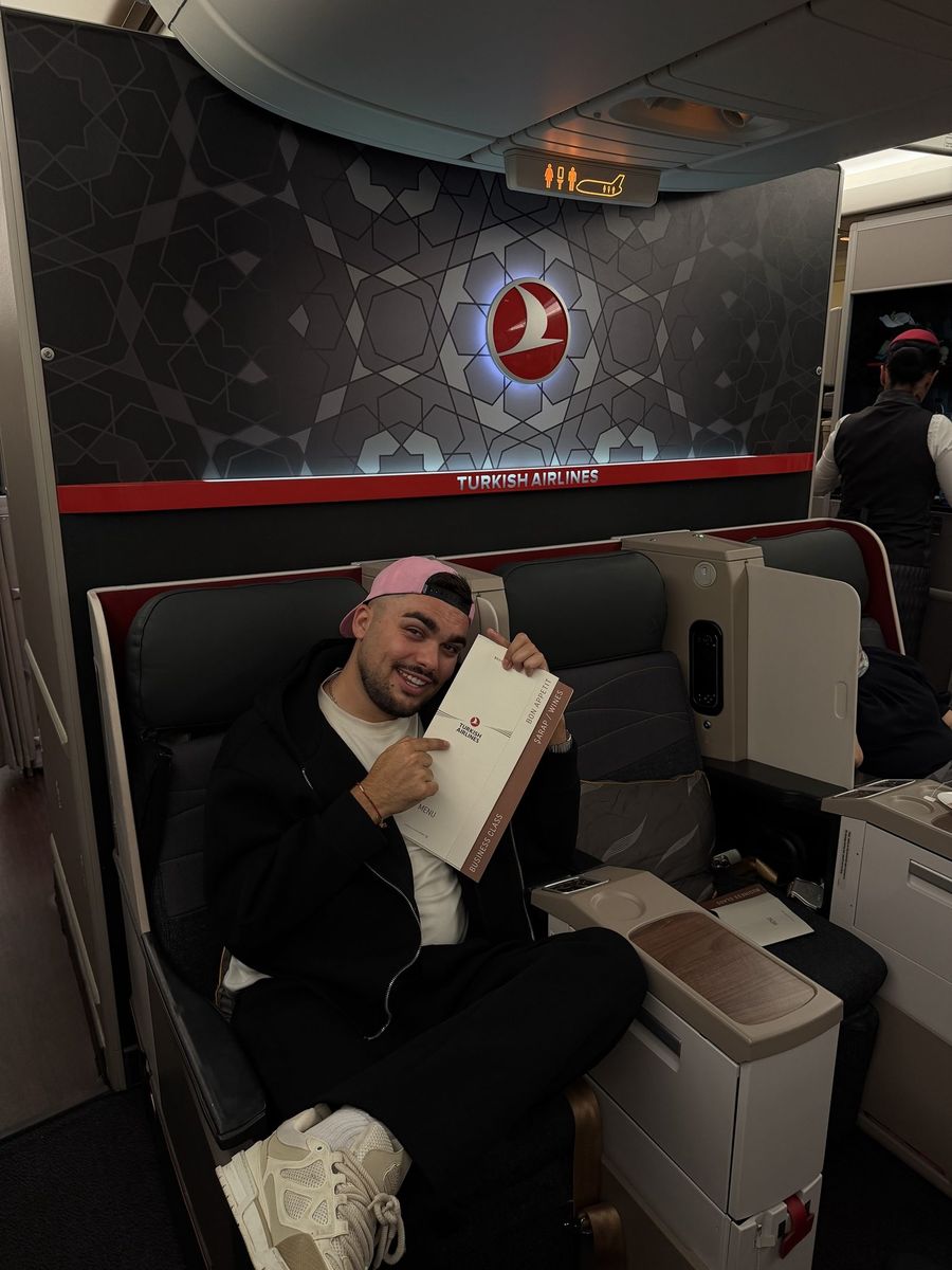 Passager installé en classe affaires Turkish Airlines, menu business à la main, devant la cloison illuminée aux motifs turcs