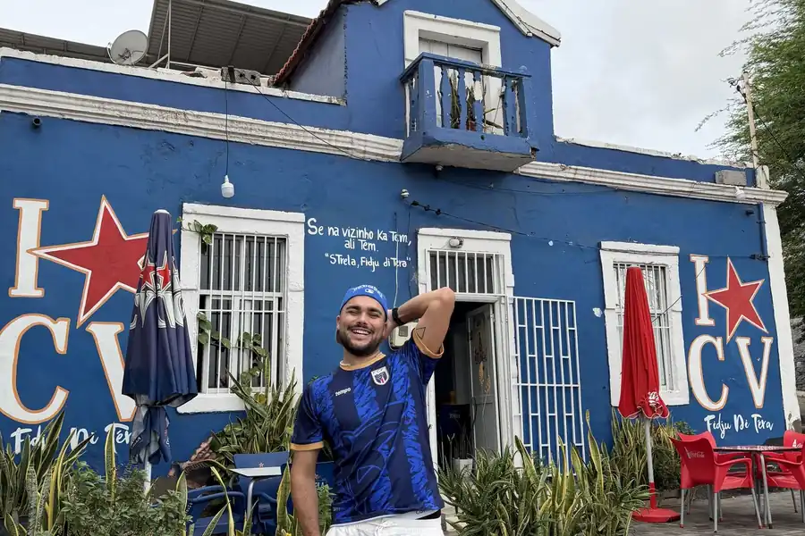 Lucas, maillot de l'équipe nationale capverdienne sur les épaules, devant une fresque colorée dans les rues de Praia, la capitale du Cap-Vert