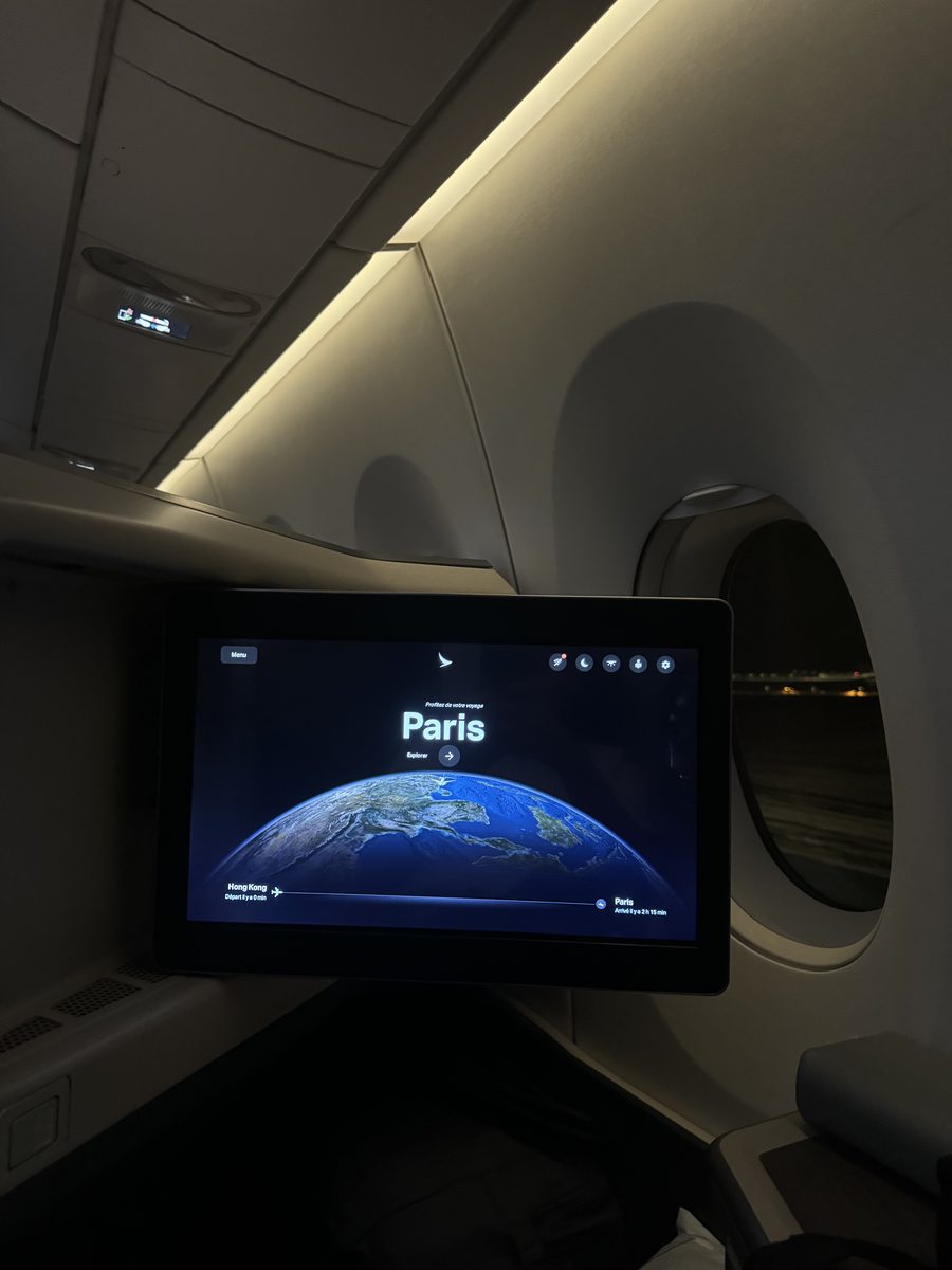Écran de divertissement de la business class de l'A350 Cathay Pacific affichant le trajet Hong Kong–Paris, hublot et lumière d'ambiance