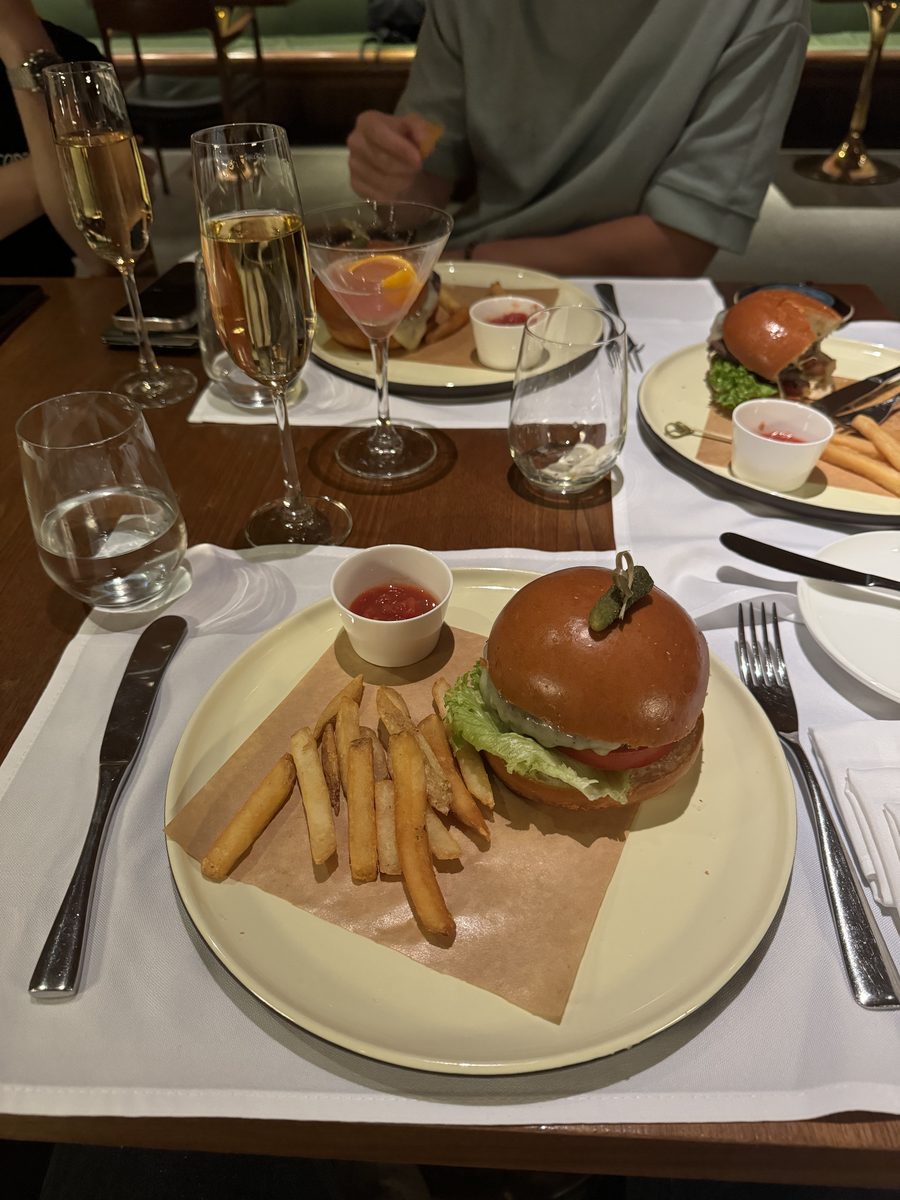 Assiette de burger et frites avec une coupe de champagne sur une table de restaurant au salon Cathay Pacific de Hong Kong