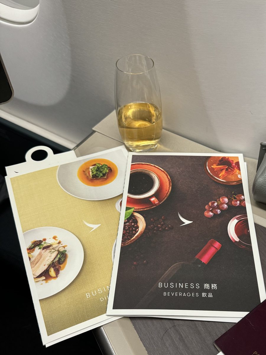 Les deux menus Business de Cathay Pacific, une coupe de champagne et la trousse Bamford posés sur la tablette du siège