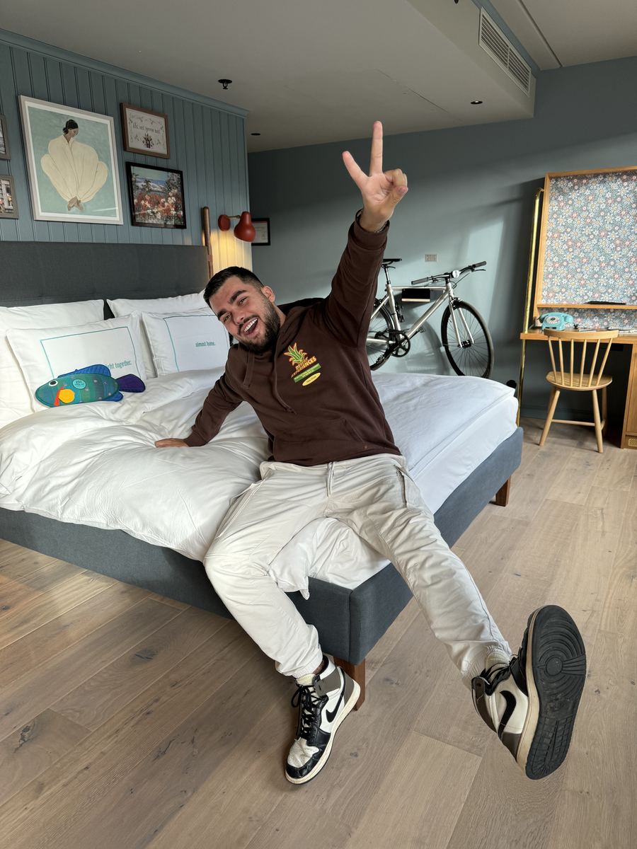 Chambre du 25hours Hotel à Copenhague avec ses murs bleu-gris, ses affiches, un vélo au mur et un téléphone à cadran turquoise
