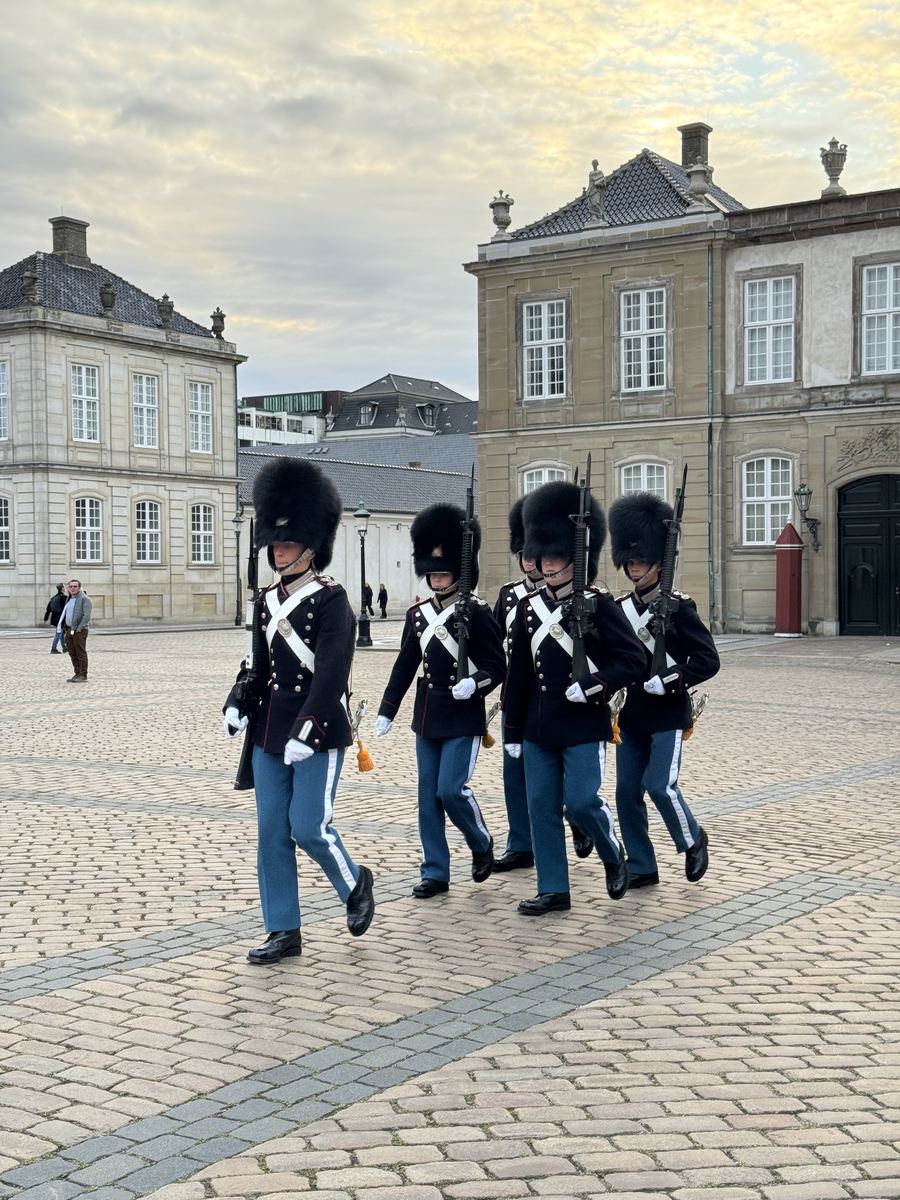 Gardes royaux danois en bonnet d'ourson marchant au pas sur la place du palais d'Amalienborg à Copenhague