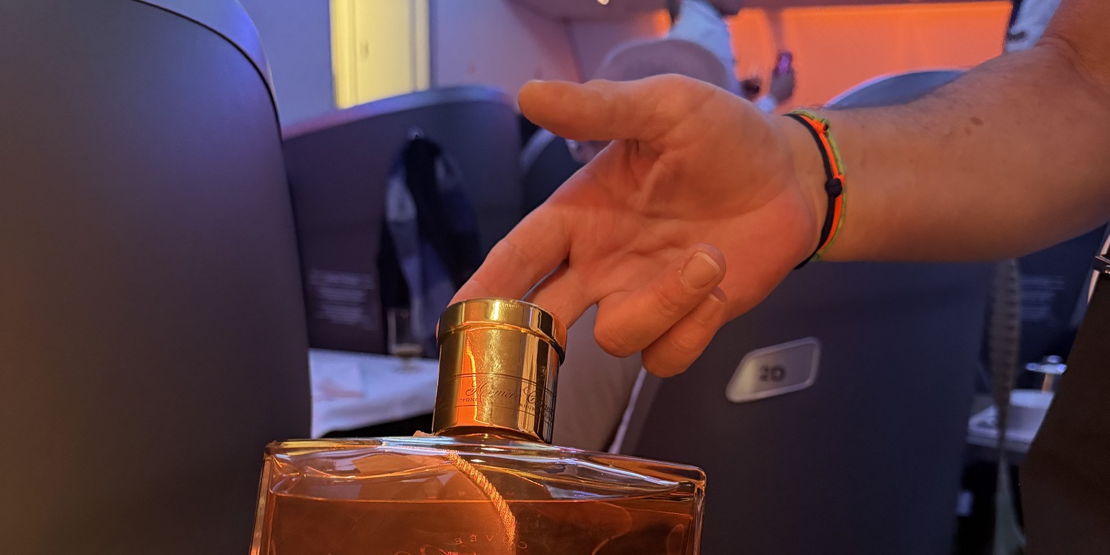 Membre d'équipage Corsair présentant une bouteille de rhum arrangé en classe affaires