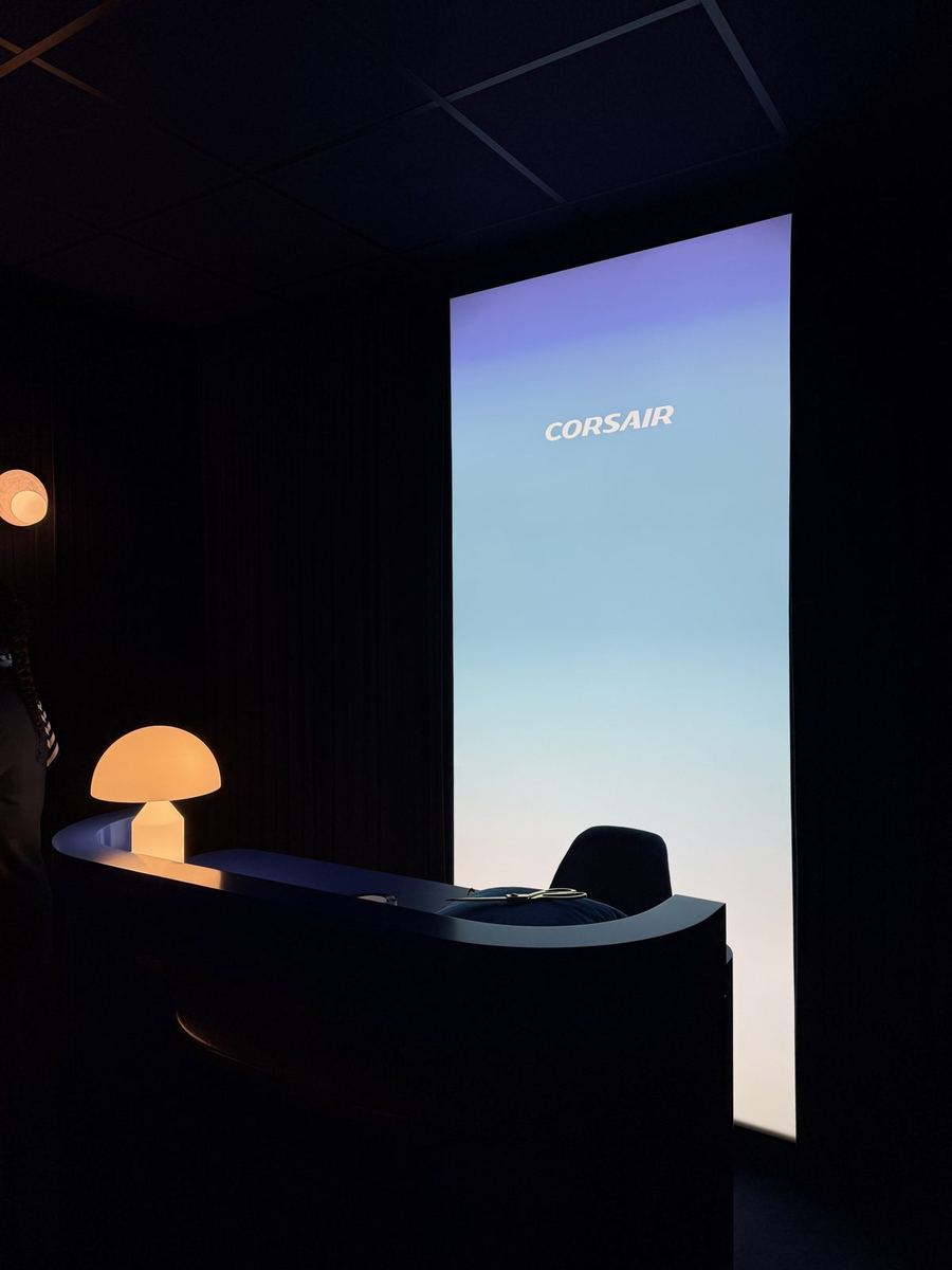 Comptoir d'accueil arrondi bleu nuit du salon Corsair, avec une lampe champignon et un grand panneau lumineux dégradé du violet au blanc