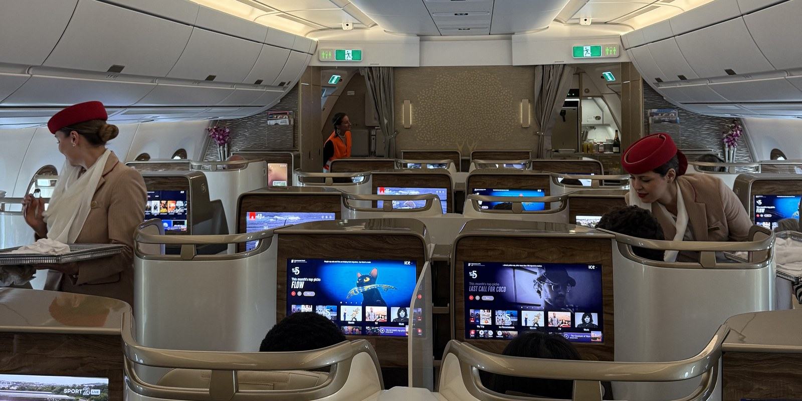 Hôtesses Emirates en uniforme crème et chapeau rouge dans la cabine affaires de l'A350