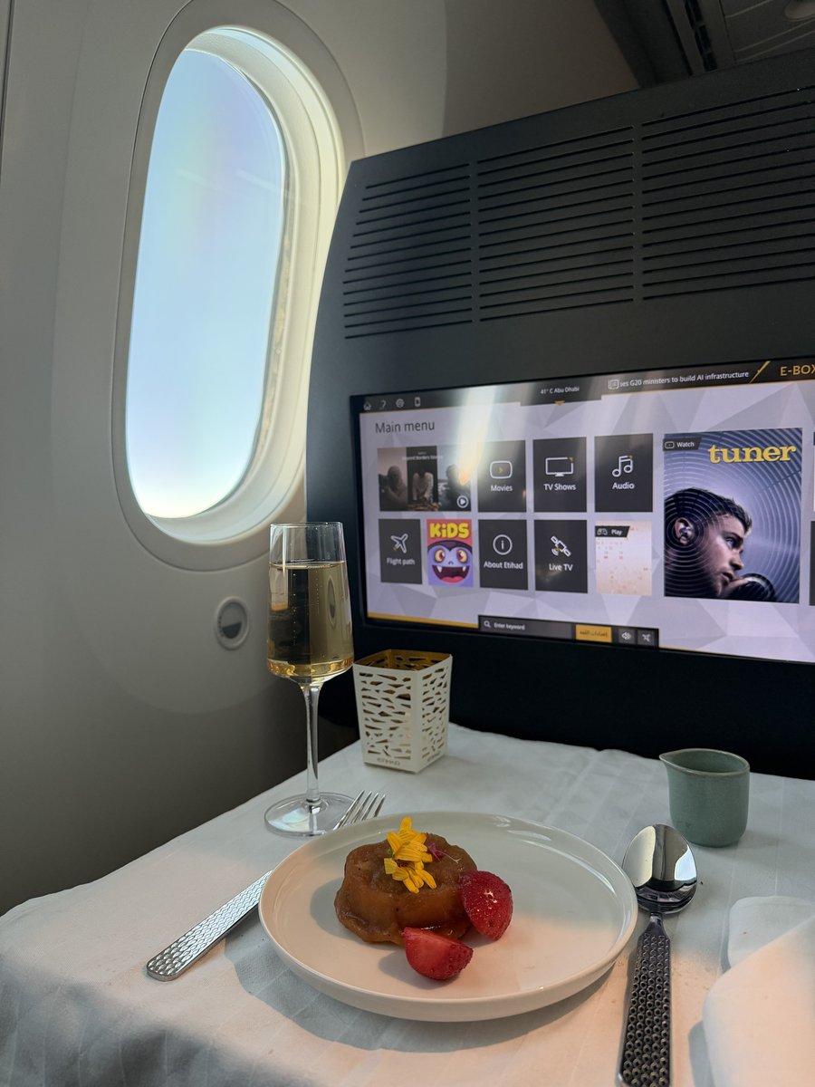 Dessert caramélisé garni de fleurs comestibles et de fraises fraîches, servi avec une coupe de champagne en business class Etihad