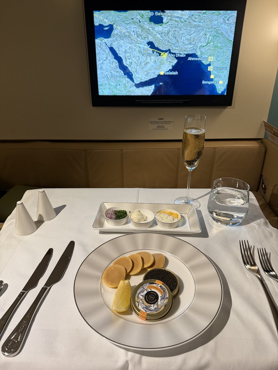 Caviar Oscietra Gourmet House servi avec blinis, garnitures et une coupe de champagne sur une table dressée en first class Etihad