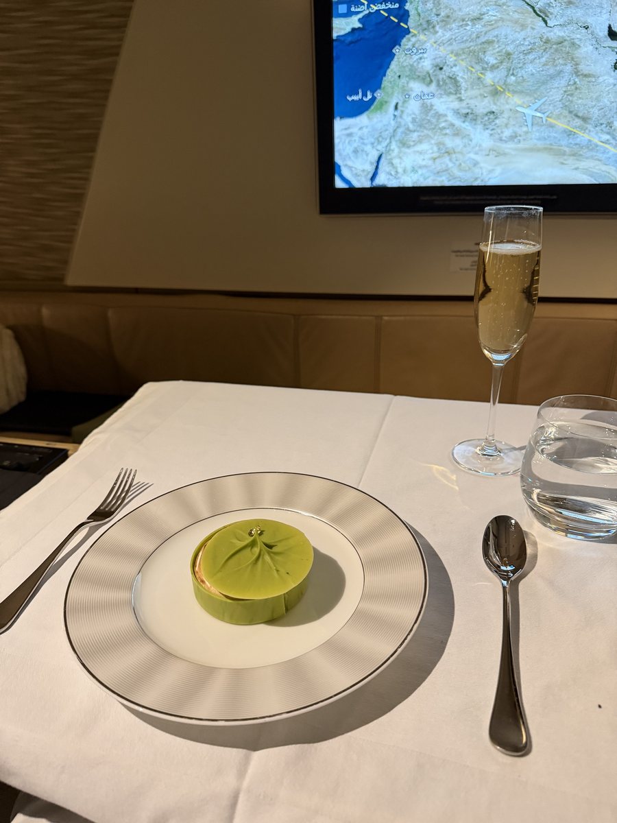 Tarte au citron servie en first class Etihad, sous un dôme de chocolat blanc vert pâle surmonté de deux perles dorées, sur assiette à filet argenté