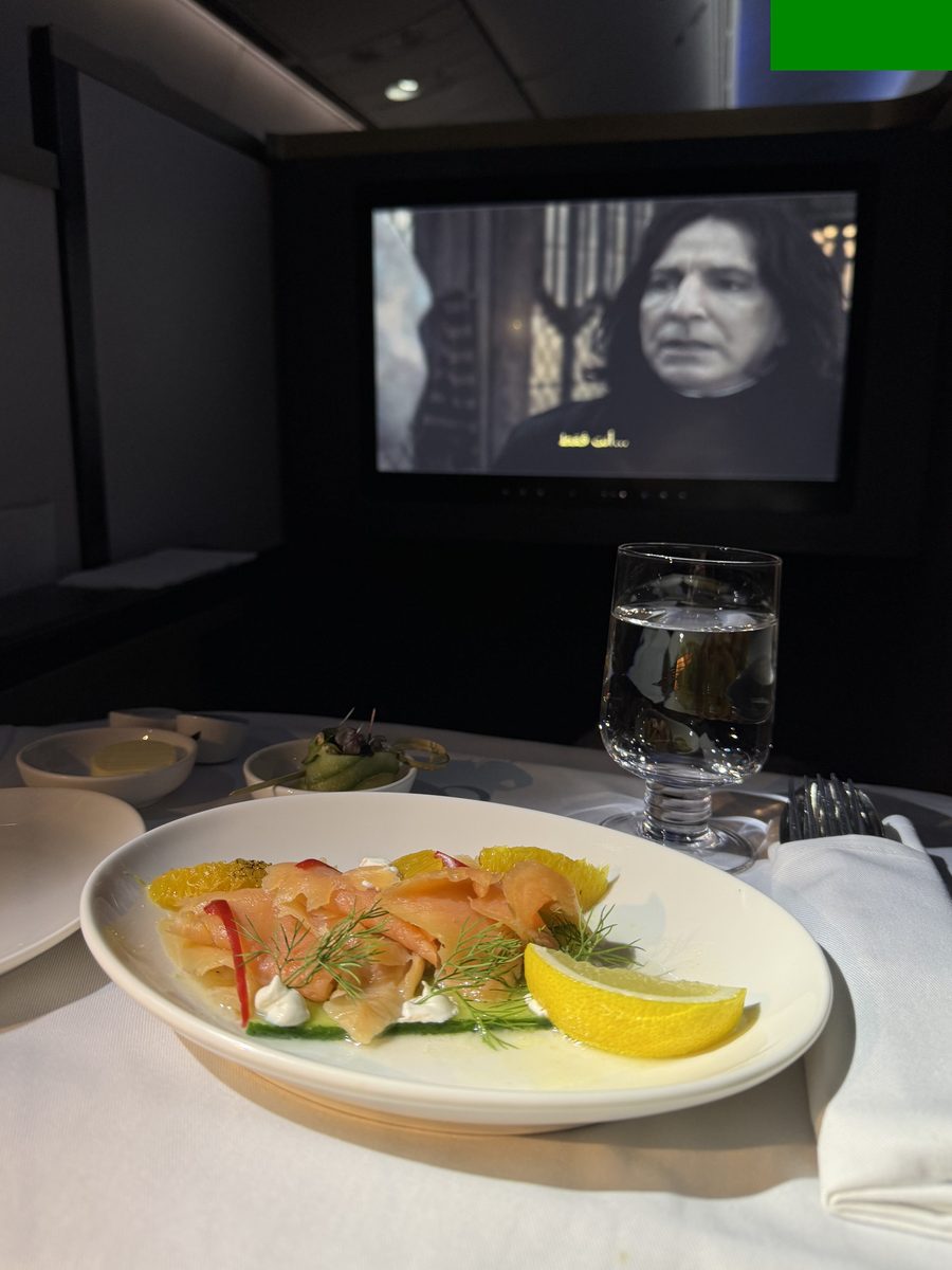 Assiette de saumon fumé aux agrumes servie sur nappe dans la suite business du 787 Gulf Air, un film à l'écran