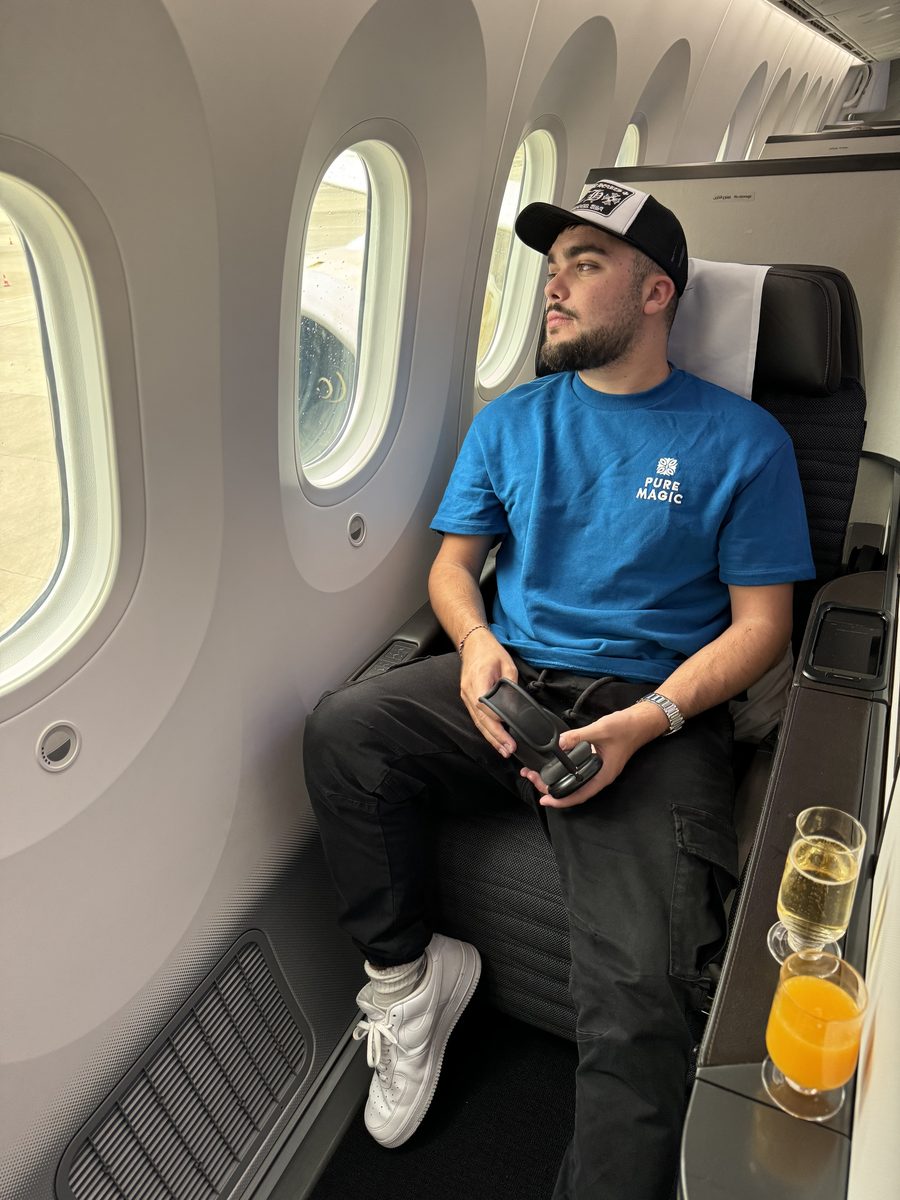 Monsieur Voyage installé dans une Apex Suite côté hublot du Boeing 787 de Gulf Air, coupe de champagne et jus d'orange sur la tablette