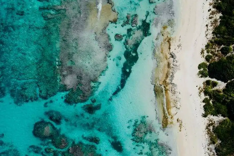 Vue aérienne d'une plage déserte aux eaux turquoise et à la barrière de corail