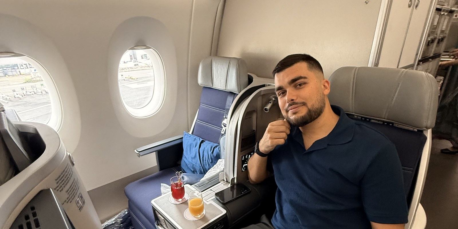 Passager installé en classe affaires Malaysia Airlines, deux boissons sur la tablette