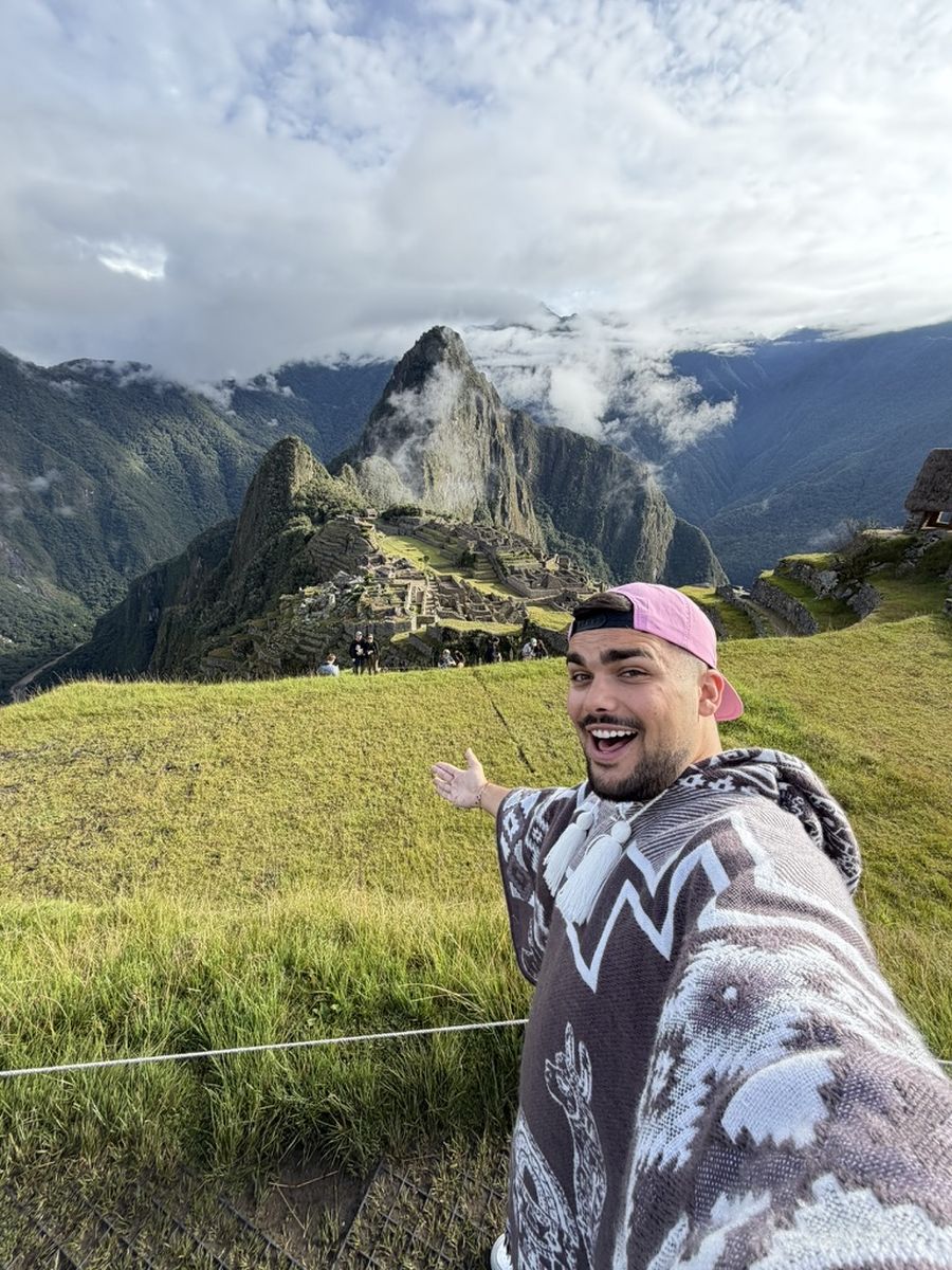 Moi en poncho andin devant la citadelle du Machu Picchu au petit matin, les terrasses presque vides derrière