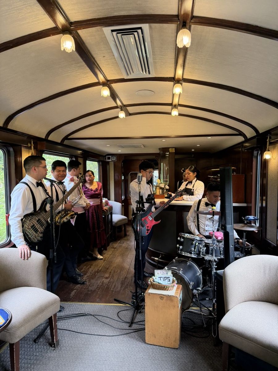 Musiciens jouant en live dans le wagon-bar du train Vistadome, avec bar, batterie et fauteuils crème