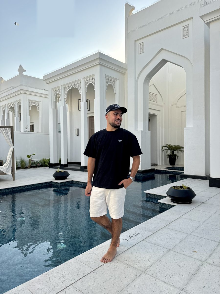 Monsieur Voyage pieds nus au bord de la piscine privée de sa villa blanche au Raffles Al Areen Palace Bahrain