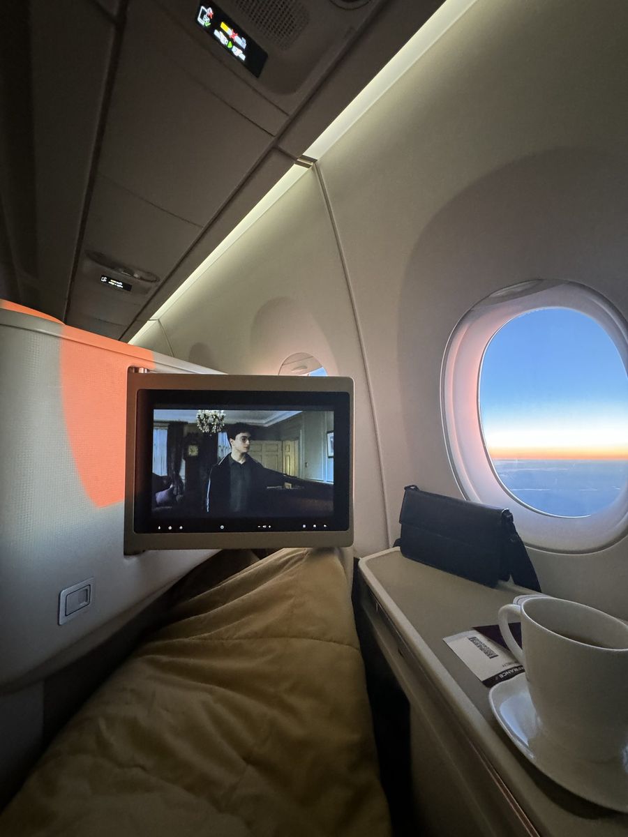 Carte d'embarquement posée sur la tablette et écran individuel diffusant un film, hublot ouvert sur un coucher de soleil à bord de la classe affaires Vietnam Airlines